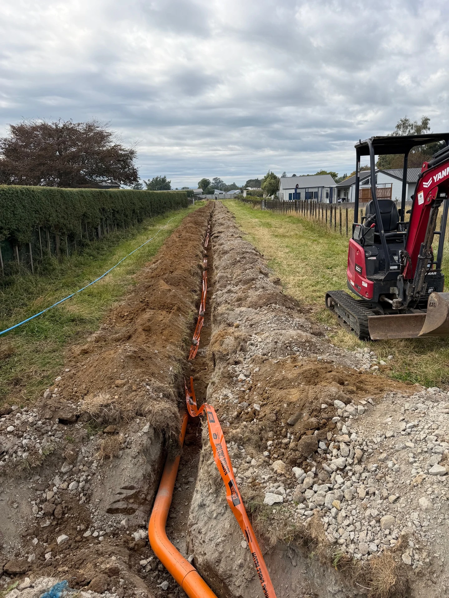 Underground electrical conduit laid in a trench beside an excavator